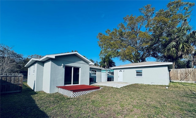 back of property with a yard, an outdoor structure, stucco siding, and fence