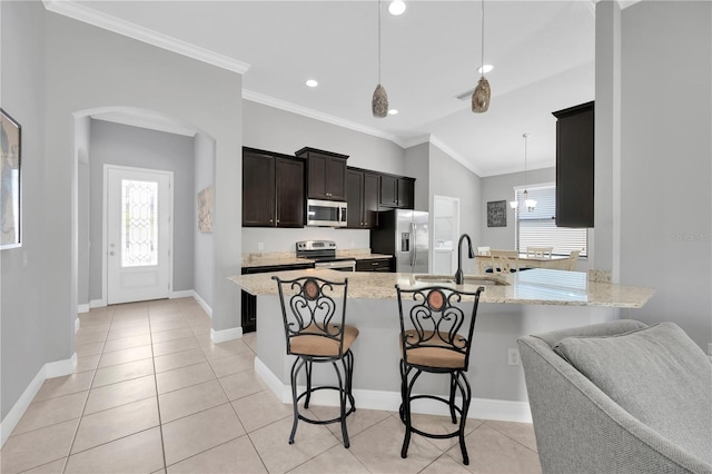 kitchen with ornamental molding, a sink, a peninsula, appliances with stainless steel finishes, and a breakfast bar area