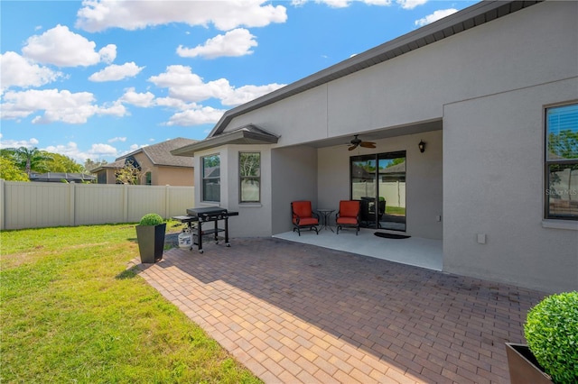 view of patio featuring a grill, ceiling fan, and fence