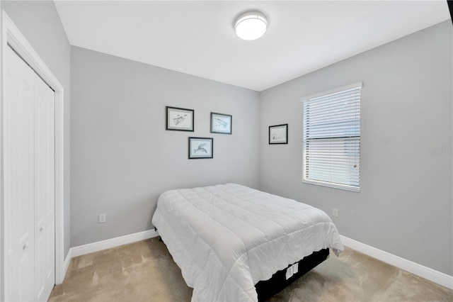 bedroom with light carpet, a closet, and baseboards