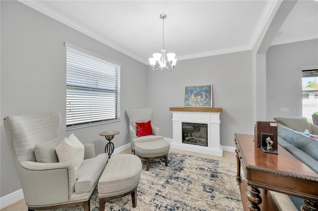 sitting room featuring a chandelier, a glass covered fireplace, baseboards, and ornamental molding