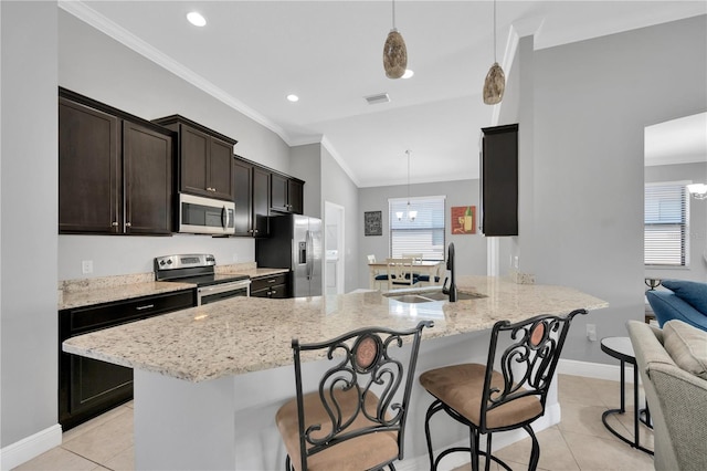 kitchen with light tile patterned floors, ornamental molding, a sink, appliances with stainless steel finishes, and a kitchen breakfast bar