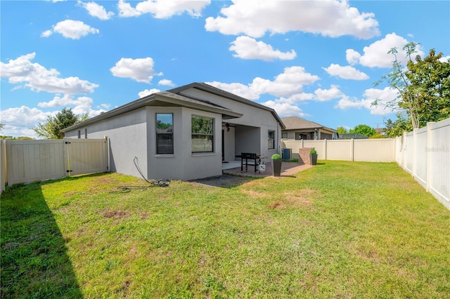 back of property featuring stucco siding, a yard, a fenced backyard, a patio area, and a gate