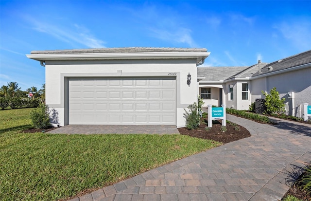 view of front of house featuring stucco siding, decorative driveway, an attached garage, and a front yard