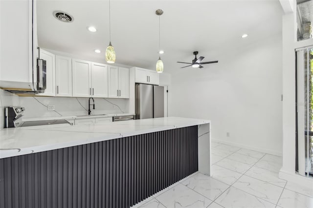 kitchen with a sink, a peninsula, marble finish floor, and stainless steel appliances