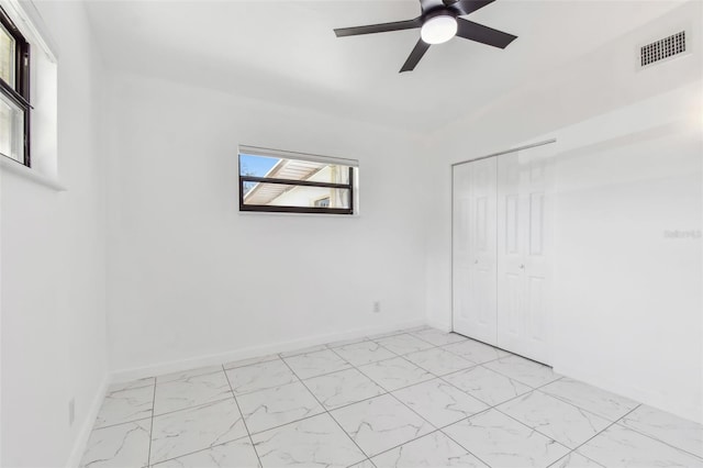empty room with visible vents, baseboards, marble finish floor, and ceiling fan