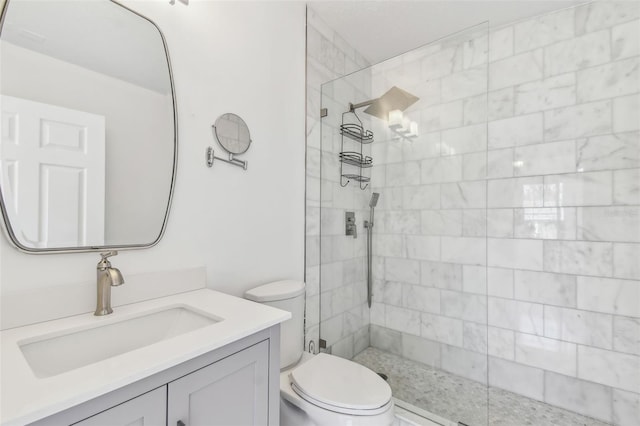 bathroom with tiled shower, toilet, and vanity