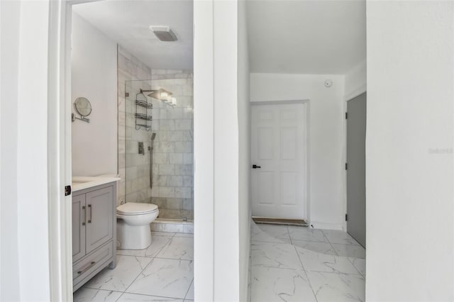 bathroom with marble finish floor, vanity, a shower stall, and toilet