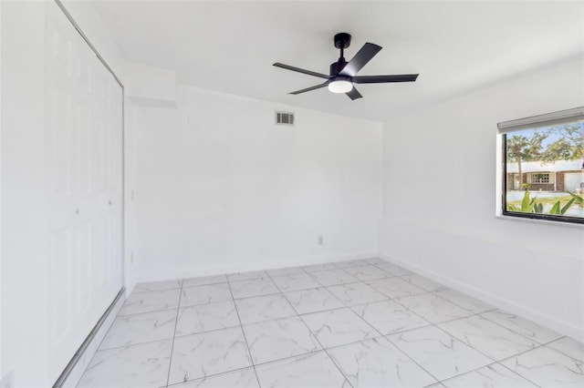 empty room featuring visible vents, baseboards, marble finish floor, and a ceiling fan