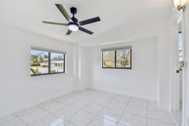 unfurnished room with plenty of natural light, baseboards, and marble finish floor