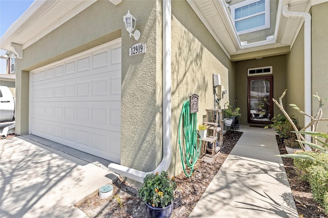 view of exterior entry with stucco siding and a garage