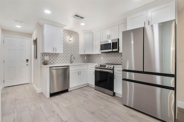 kitchen with stainless steel appliances, tasteful backsplash, visible vents, and white cabinets