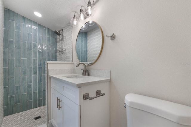 full bath featuring a tile shower, toilet, and vanity