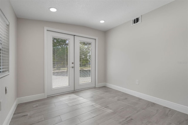 empty room with visible vents, a textured ceiling, recessed lighting, french doors, and baseboards