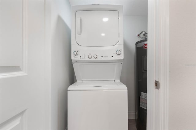 washroom featuring stacked washer / drying machine, water heater, and laundry area