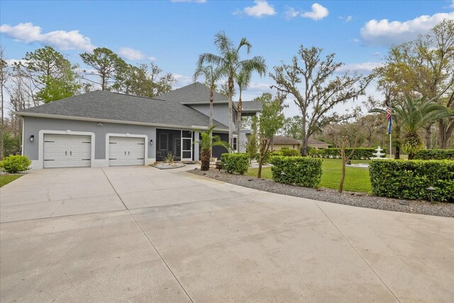 view of front facade featuring driveway, an attached garage, a shingled roof, stucco siding, and a front lawn