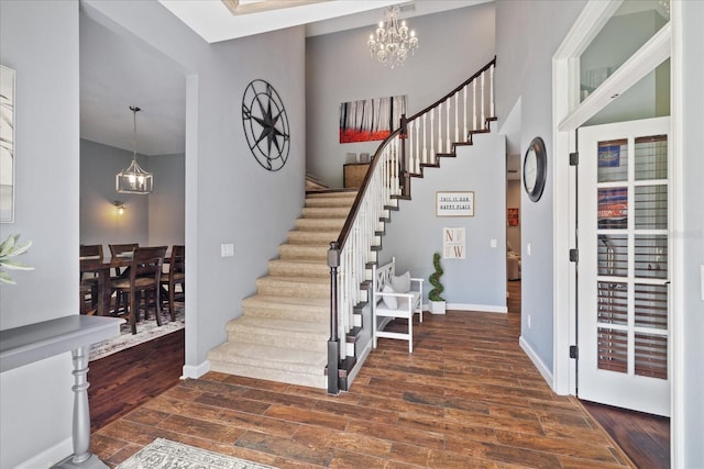 entryway with baseboards, stairs, an inviting chandelier, and wood finished floors