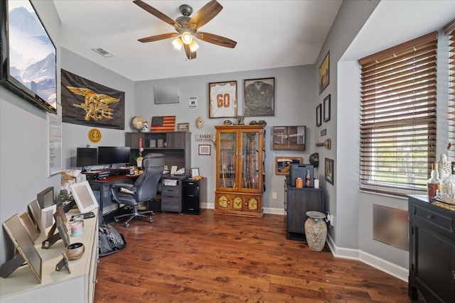 home office featuring wood finished floors, a ceiling fan, visible vents, and baseboards