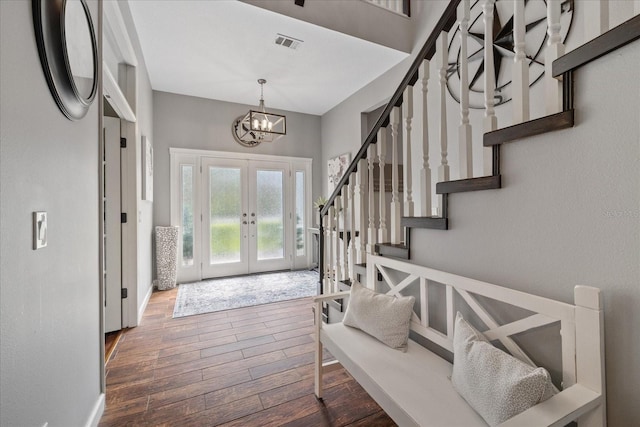 foyer entrance with visible vents, a chandelier, stairs, hardwood / wood-style floors, and french doors