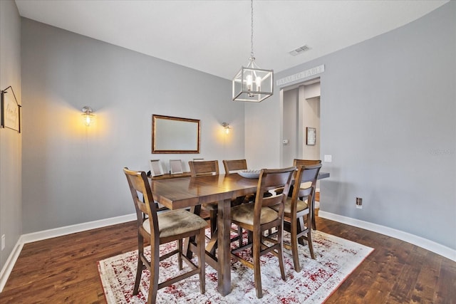 dining area with baseboards, wood finished floors, visible vents, and a chandelier