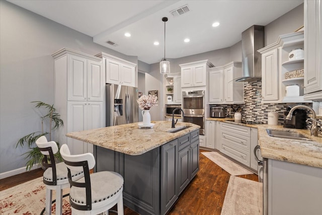 kitchen with visible vents, open shelves, a sink, stainless steel appliances, and wall chimney range hood