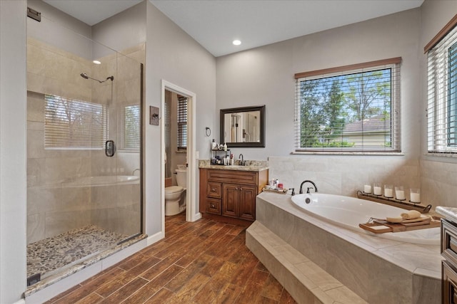 full bath featuring a bath, a shower stall, toilet, and wood finished floors