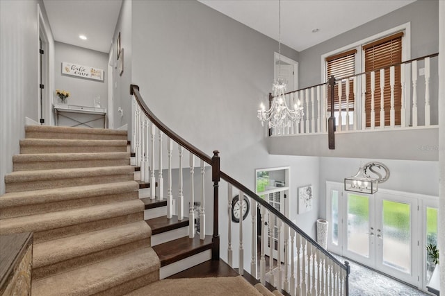 stairs with french doors, an inviting chandelier, and a towering ceiling