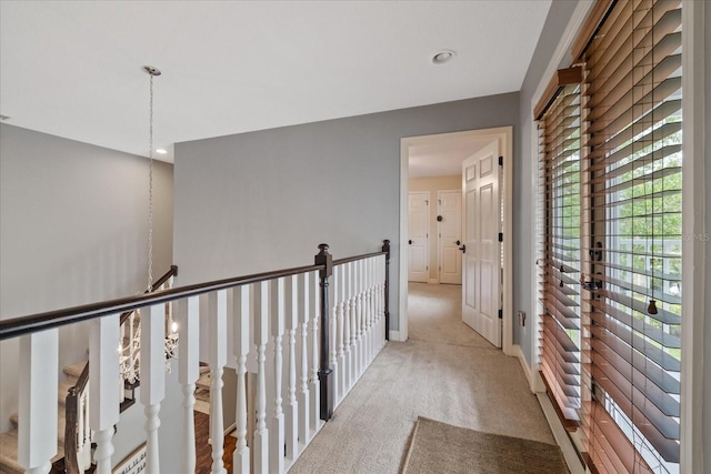 hall featuring recessed lighting, baseboards, an upstairs landing, and light colored carpet