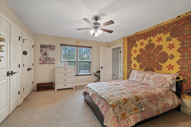 bedroom featuring baseboards, light colored carpet, a textured ceiling, and multiple closets