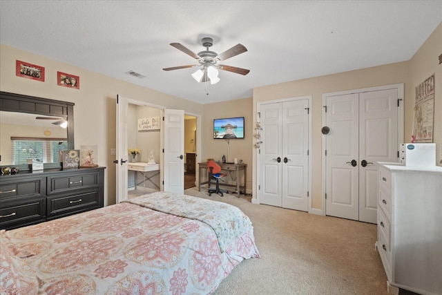 bedroom featuring visible vents, two closets, baseboards, light carpet, and a ceiling fan