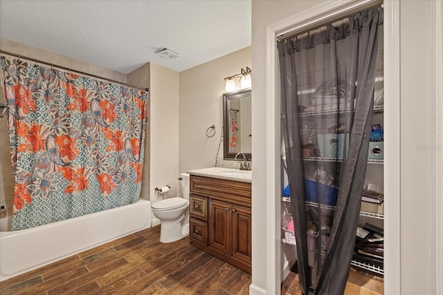 full bathroom featuring toilet, shower / bath combo, a textured ceiling, wood finished floors, and vanity