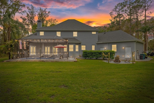 back of house at dusk featuring a lanai, a fire pit, a chimney, and a patio