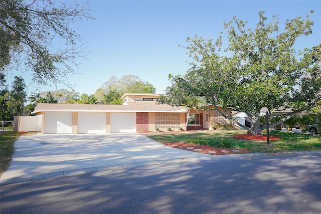 view of front of property featuring stucco siding, driveway, a garage, and fence