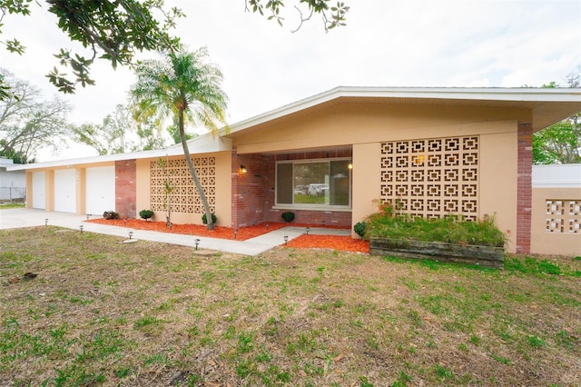 ranch-style house featuring a front lawn, a garage, brick siding, and driveway