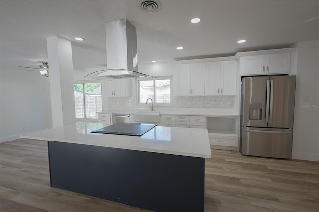 kitchen with visible vents, island exhaust hood, a sink, backsplash, and appliances with stainless steel finishes