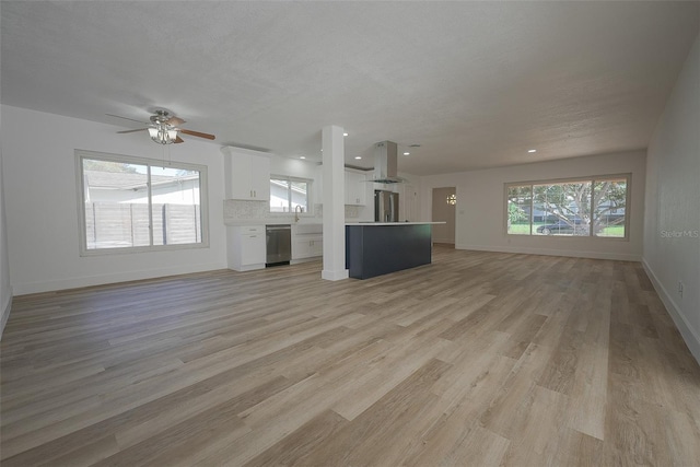 unfurnished living room featuring a healthy amount of sunlight, light wood-type flooring, and a sink