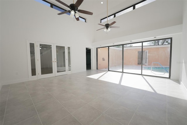 tiled spare room with french doors, a towering ceiling, and ceiling fan