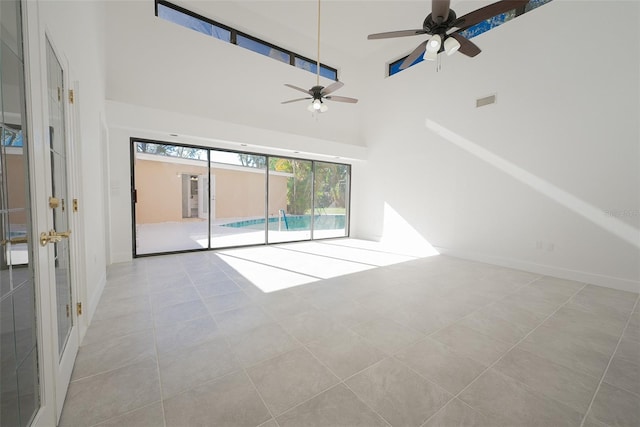 tiled spare room featuring visible vents, baseboards, and a towering ceiling