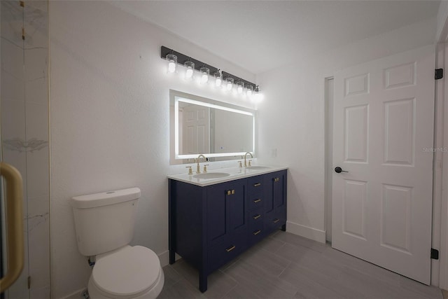 bathroom with a sink, baseboards, toilet, and double vanity