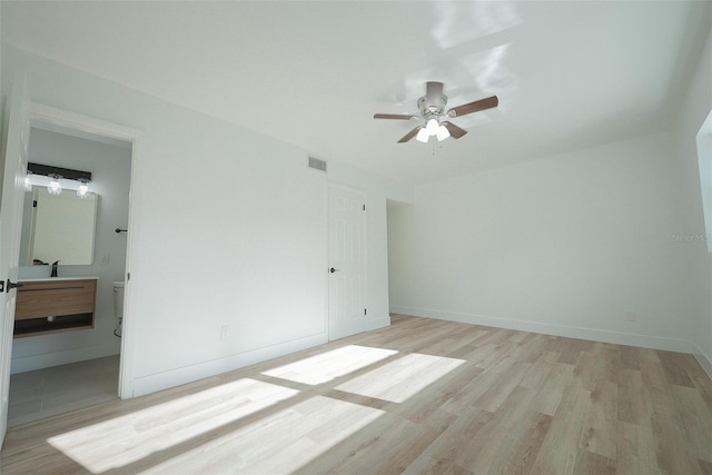 unfurnished bedroom with a ceiling fan, visible vents, baseboards, light wood-style floors, and connected bathroom