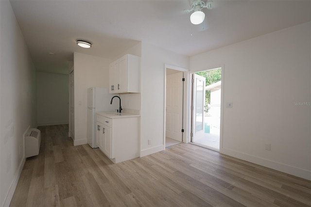 kitchen with baseboards, light countertops, freestanding refrigerator, light wood-style floors, and white cabinetry