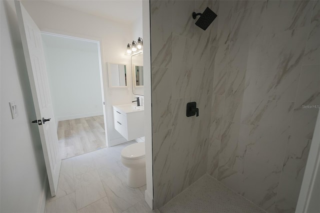 full bathroom with a tile shower, toilet, vanity, and marble finish floor