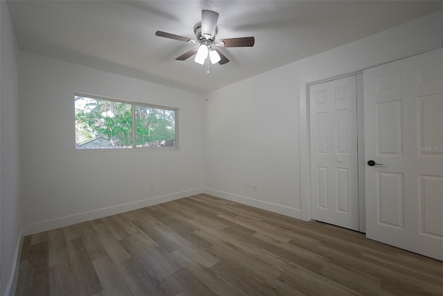 unfurnished bedroom featuring a closet, a ceiling fan, baseboards, and wood finished floors