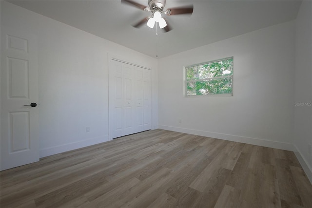 spare room with a ceiling fan, light wood-style floors, and baseboards