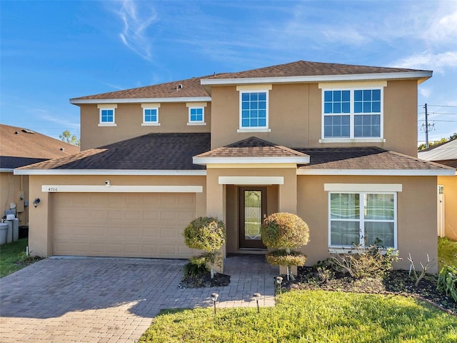 traditional-style house featuring decorative driveway, a garage, and stucco siding