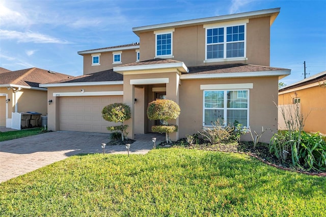 traditional home with a shingled roof, a front lawn, stucco siding, a garage, and driveway