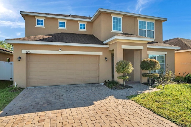 view of front facade featuring stucco siding, a garage, roof with shingles, and driveway