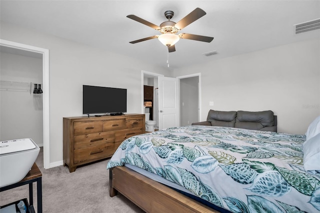 bedroom featuring a spacious closet, visible vents, a closet, and light carpet