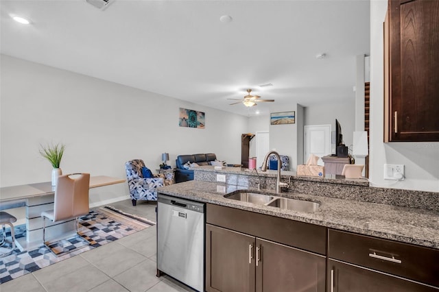 kitchen with a sink, light stone counters, stainless steel dishwasher, dark brown cabinets, and ceiling fan