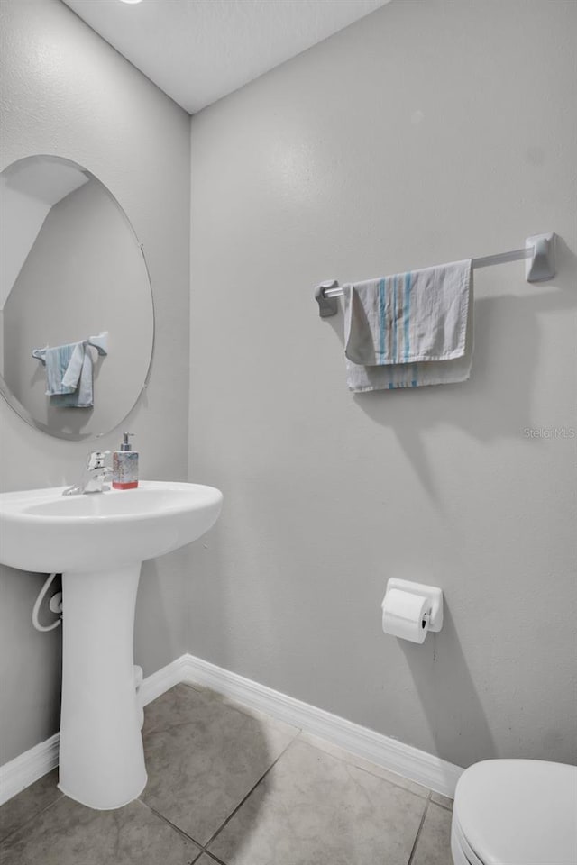 bathroom with tile patterned floors, toilet, and baseboards